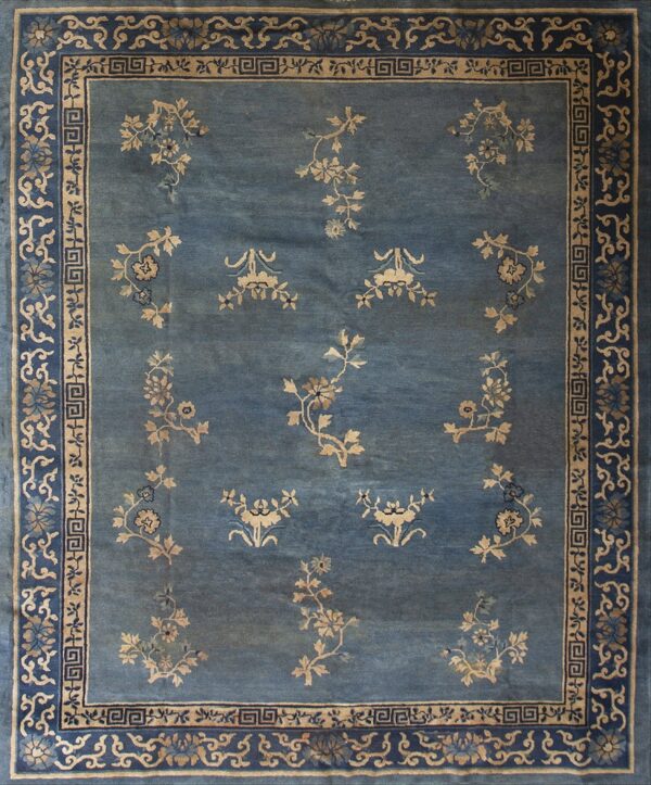 The rug is slate blue with scattered tan floral sprays and intricate blue and beige borders.