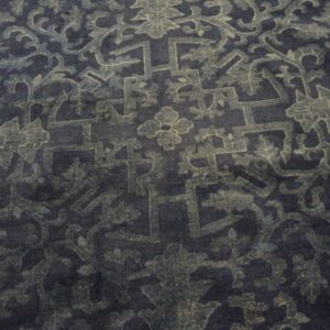 Dark blue rug with a muted teal and grey traditional pattern of intertwining florals and angular motifs.