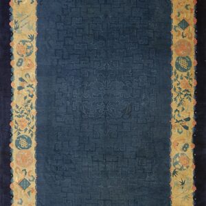 Full overhead view of a dark blue rug with a geometric pattern and a light gold border detailed with salmon florals.