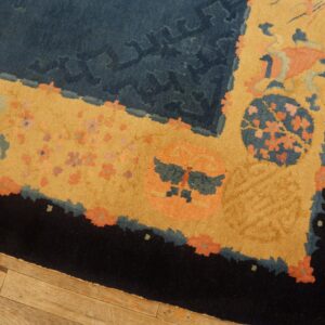 Close view of a high-pile rug with navy, gold, coral, and black borders resting on a light wood floor.