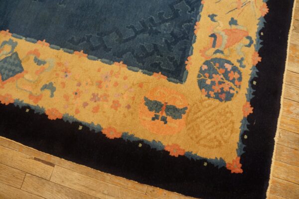 Close view of a high-pile rug with navy, gold, coral, and black borders resting on a light wood floor.