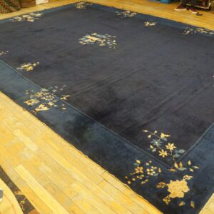 Large low-pile indigo rug featuring a wide blue border and scattered pale yellow botanical motifs.