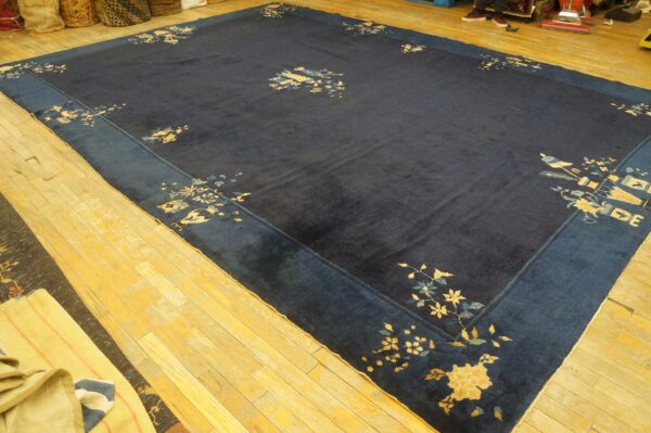 Large low-pile indigo rug featuring a wide blue border and scattered pale yellow botanical motifs.