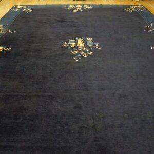 A deep navy blue rug features stylized floral and figural motifs, displayed on light wood floors.