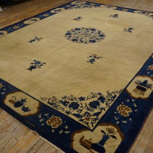 Cream rug featuring a blue floral medallion, scattered motifs, and a wide blue patterned border on rustic wood floors.