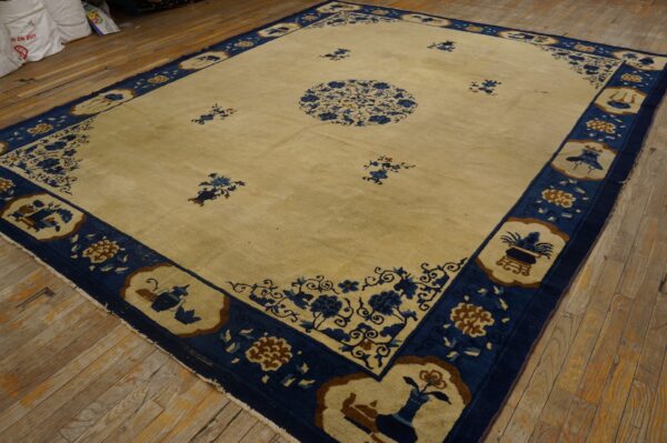 Cream rug featuring a blue floral medallion, scattered motifs, and a wide blue patterned border on rustic wood floors.