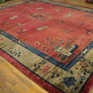 Muted pink rug with scattered patterns, blue detailing, and a sage green floral border on wood floors.