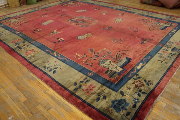 Muted pink rug with scattered patterns, blue detailing, and a sage green floral border on wood floors.