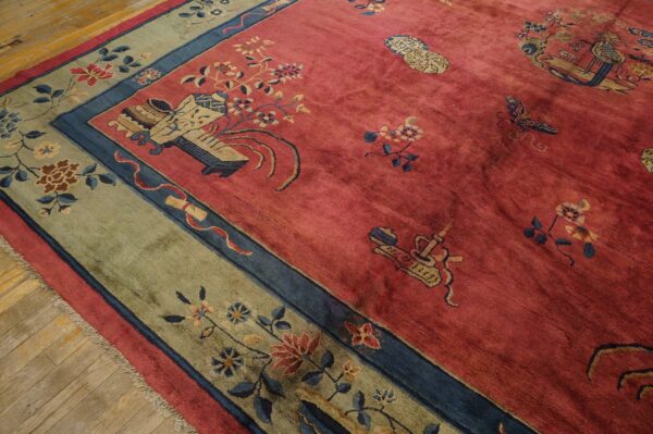 Muted red high-pile rug with blue, beige, and green floral patterns rests on light hardwood flooring.