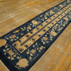 Blue and tan floral runner rug rests on distressed, warm-toned hardwood plank flooring.