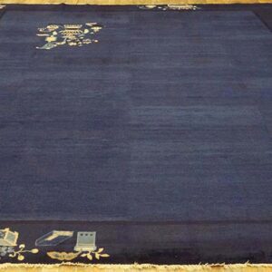 Deep navy rug with light pictorial corner and center motifs displayed on light wood floorboards.