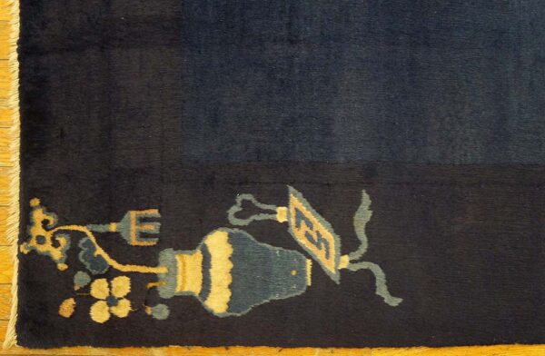 Deep navy rug edge features a border of stylized yellow and teal floral and vessel motifs on wood flooring.