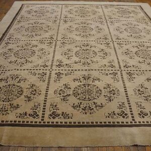 Tan rug featuring a repeating grid pattern of dark brown traditional medallions on wood flooring.
