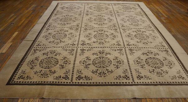 Tan rug featuring a repeating grid pattern of dark brown traditional medallions on wood flooring.
