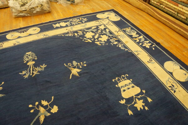 Navy blue rug with a wide cream border featuring stylized flowers and bird motifs on wood flooring.