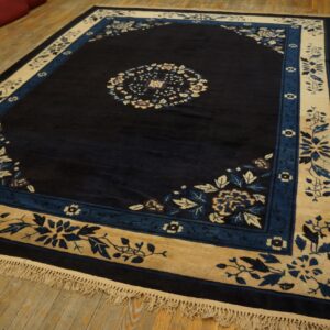 Deep navy rug with cream and blue floral borders features a central medallion on plank hardwood floors.