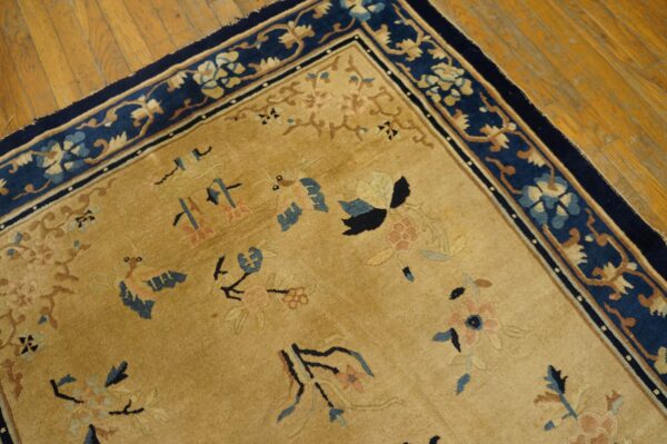 Antique peking chinese floral beige 1890s rug 8 Tan rug with scattered blue and pink patterns, contrasted by a bold navy floral border on wood floors.