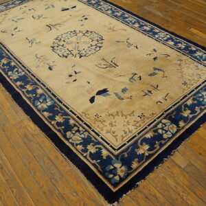 Beige rug featuring scattered blue and tan floral designs and a wide navy border on distressed wood planks.