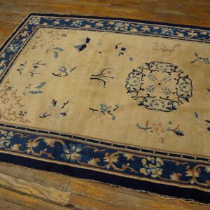 Gold and dark blue rug with scattered bird and blossom designs lies on rustic plank flooring.