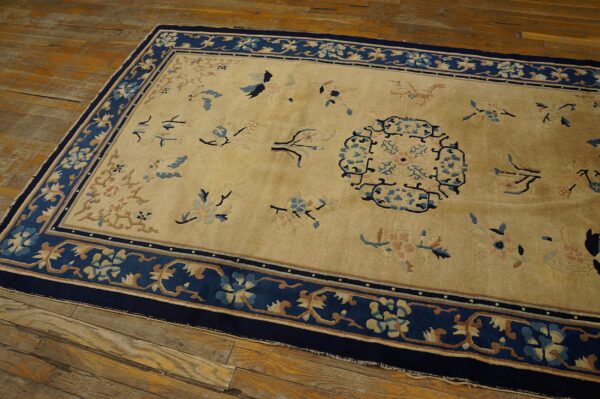 Antique peking chinese floral beige 1890s rug 4 Gold and dark blue rug with scattered bird and blossom designs lies on rustic plank flooring.