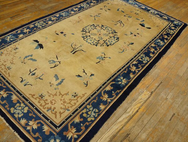 Antique peking chinese floral beige 1890s rug 6 Rectangular gold rug with a navy border, scattered flowers, and a central medallion on wood planks.