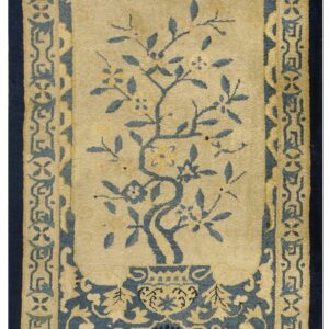 Beige rug with a central blue tree in a vase and intricate blue and tan geometric borders.