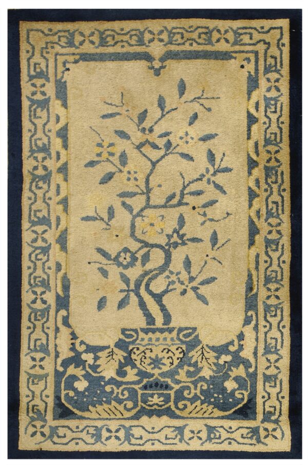 Beige rug with a central blue tree in a vase and intricate blue and tan geometric borders.
