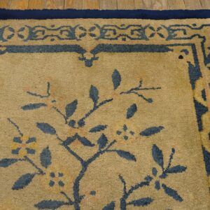 High pile rug in tan and deep blue with stylized botanical patterns borders the distressed wood floor.