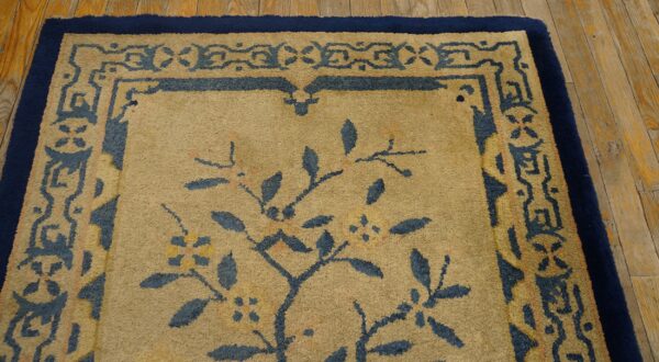 High pile rug in tan and deep blue with stylized botanical patterns borders the distressed wood floor.
