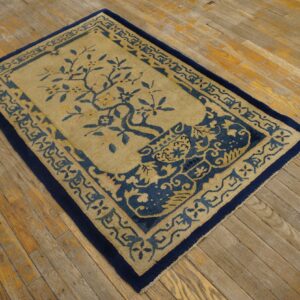 Blue and gold patterned rug with a central tree motif rests on worn wooden plank flooring.
