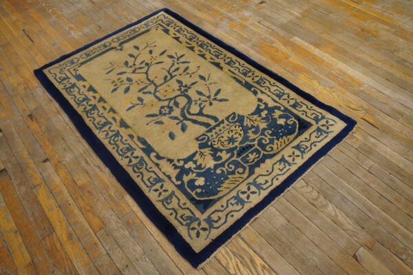 Blue and gold patterned rug with a central tree motif rests on worn wooden plank flooring.