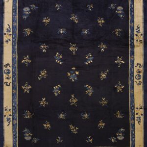Dark navy rug with scattered gold and blue floral motifs and a thick tan and blue border.