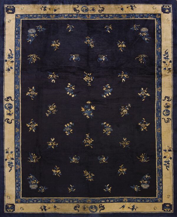 Dark navy rug with scattered gold and blue floral motifs and a thick tan and blue border.