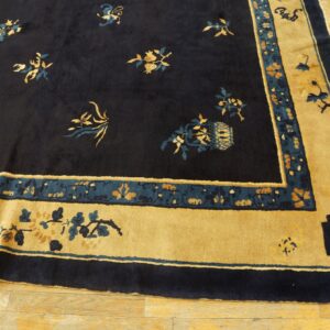 Dark navy rug with scattered gold and teal floral motifs and a wide golden yellow border on wood flooring.