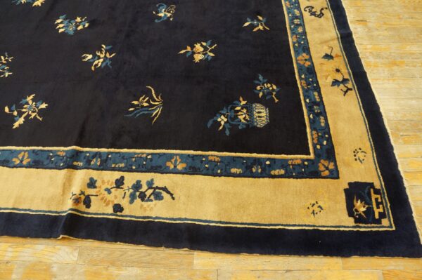 Dark navy rug with scattered gold and teal floral motifs and a wide golden yellow border on wood flooring.