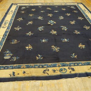 Large navy rug with scattered gold and teal designs and a wide beige border, lying on light wood floors.