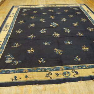 Low-pile navy rug with scattered gold and blue motifs and a thick cream border on hardwood.