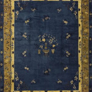 Navy blue rug with a central vase motif and gold floral sprays, framed by an elaborate gold border.