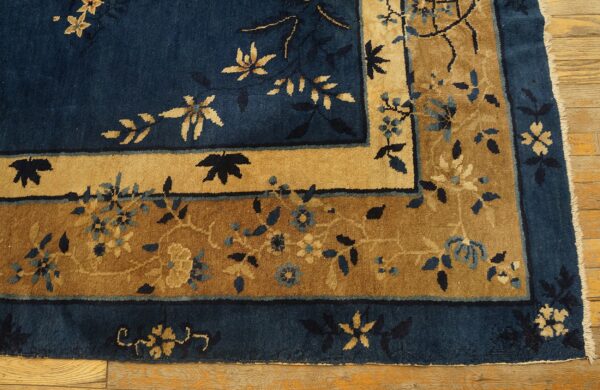 High-pile rug in deep indigo and gold features floral borders, visible over worn hardwood.