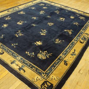 A navy blue rug with scattered gold and teal floral patterns and a wide golden yellow border rests on wood planks.