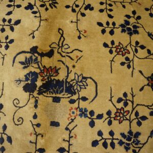 Golden beige rug with an all-over pattern of navy blue vines and small coral red flowers.