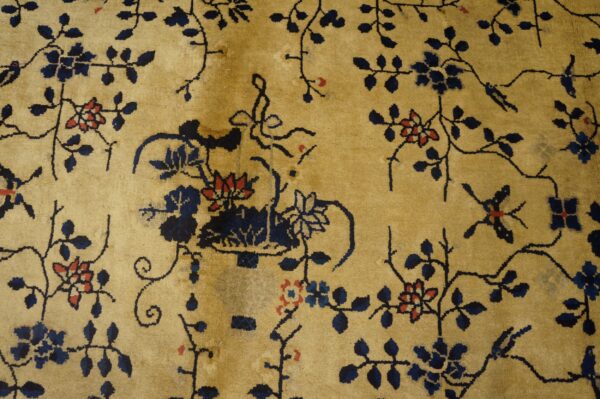 Golden beige rug with an all-over pattern of navy blue vines and small coral red flowers.