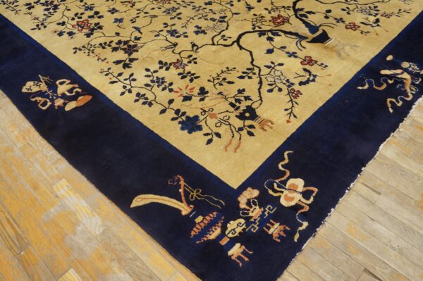 Gold field rug featuring an ornate blue floral tree design and detailed corner border on wood floors.