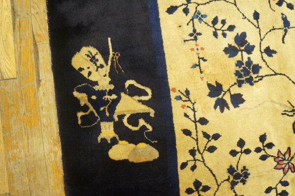 Navy blue and gold rug with a patterned figure and floral vines lying on distressed wood planks.