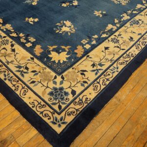 Deep blue rug with scattered florals and a wide beige, blue-patterned border on wood flooring.