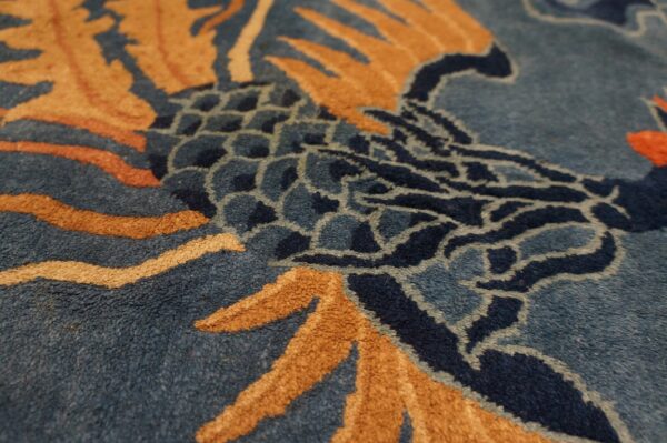 Textured high-pile rug detail displaying scales and stylized patterns in shades of blue, gold, and rust.