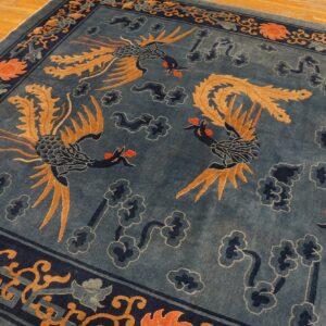 Dusty blue rug featuring large stylized birds and navy clouds, bordered by geometric patterns on wood floors.