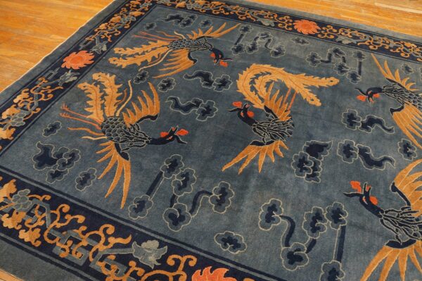 Dusty blue rug featuring large stylized birds and navy clouds, bordered by geometric patterns on wood floors.