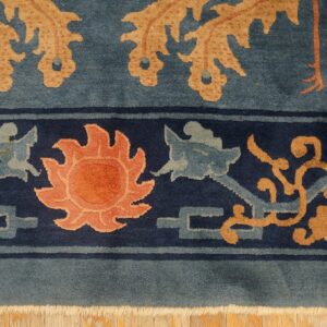 The blue rug features a navy border with a peach sun and tan motifs next to a dusty blue field.