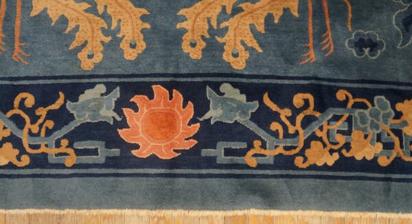 The blue rug features a navy border with a peach sun and tan motifs next to a dusty blue field.